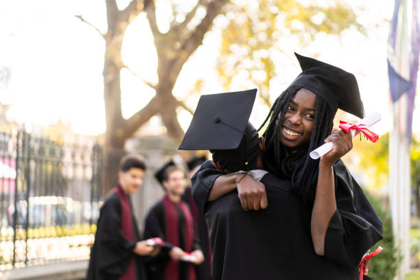 istock A graduate holding her diploma and embracing a friend 2157757129