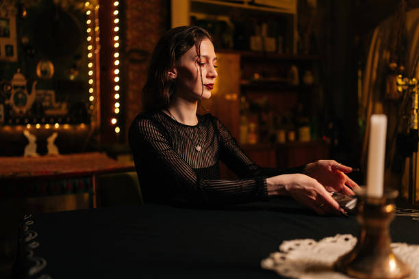 istock Mysterious fortuneteller dealing Tarot cards before forecasting future for client. Female fortune-telling having divination session with tarot cards at dark esoteric room. 2157757259