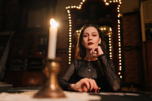 istock Enigmatic fortuneteller dealing Tarot cards forecasting future for client by light of burning candles. Mysterious wizard having divination session with tarot cards 2157757264