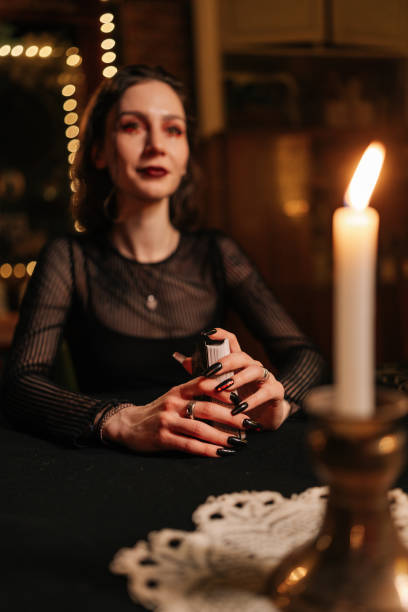 istock Vertical portrait of female soothsayer dealing Tarot cards forecasting future for client. Fortune-telling having divination session with tarot cards at dark esoteric room. 2157757265