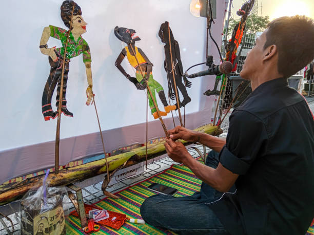 Songkhla, Thailand - December 30, 2023: A traditional Thai artist performing Nang Talung a traditional style of shadow puppetry from southern Thailand.  Nang yai features life-size puppets, while nang talung puppets are much smaller.