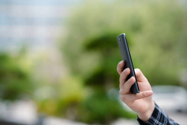 A young man's hand holding a smartphone on university campus