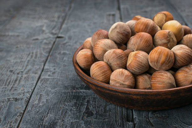 istock Rustic Wooden Bowl Filled with Raw Hazelnuts Resting on Weathered Wooden Table 2157776433