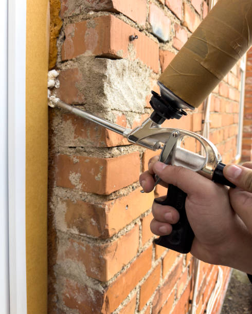 istock Window installation. The process of insulating windows with construction foam. A builder's hand seals the cracks between the building and the window frame. Construction and insulation of the building. 2157779877