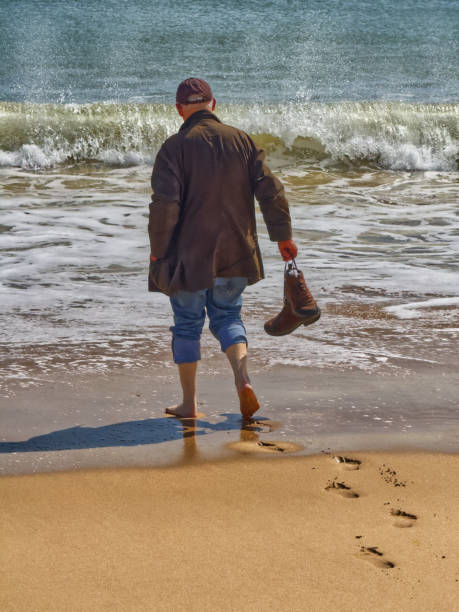 Man testing the water, carrying his boots