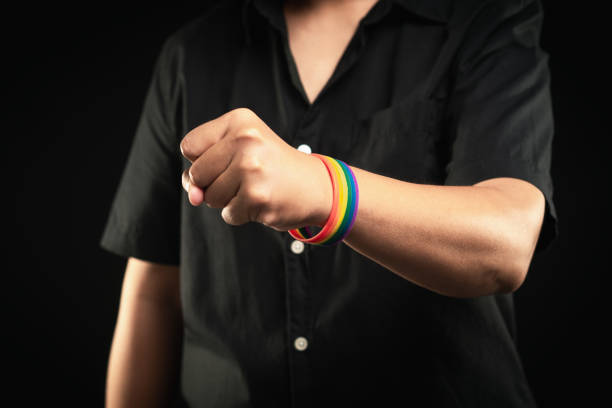 istock Hand fist with rainbow wristband in a hand while standing against a black background. 2157783840