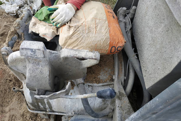 The worker mixes cement with sand in a concrete mixer.2020