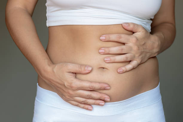 istock Stomach ache, bloating, flatulence, abdominal distension, colic, digestive disorders. Young woman holding her stomach with her hands 2157791336