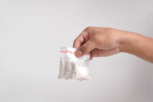 istock Hand giving cocaine in plastic package on white background 2157792590