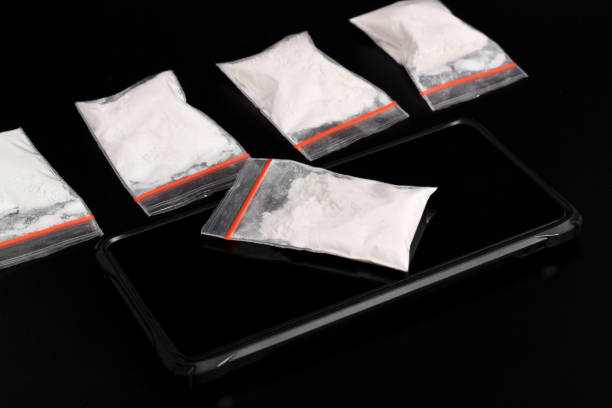 istock Cocaine in a plastic package on a smartphone on a black background. illegal drug 2157792701