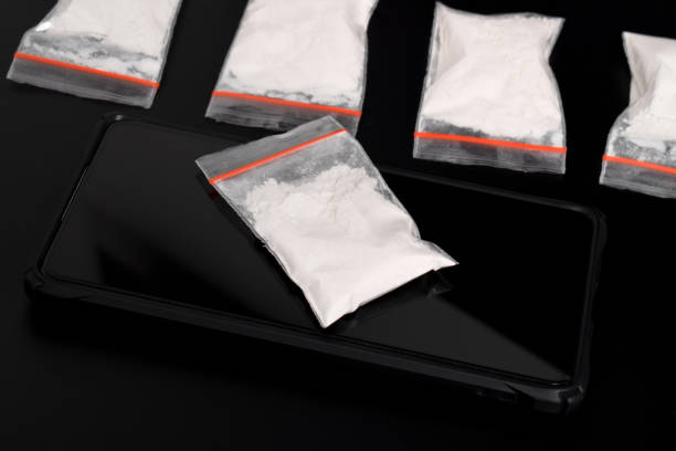 istock Cocaine in a plastic package on a smartphone on a black background. illegal drug 2157792704