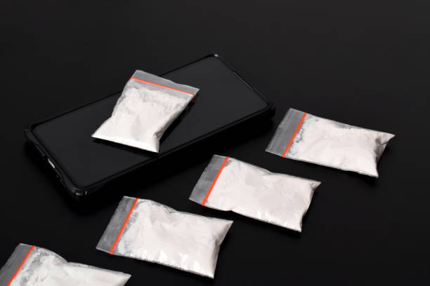istock Cocaine in a plastic package on a smartphone on a black background. illegal drug 2157792766