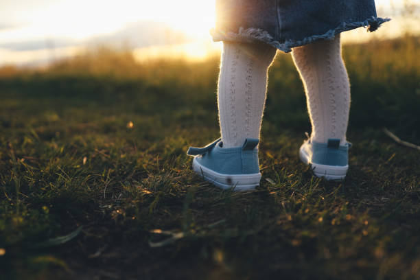 istock Babys legs are walking on grass in park at sunset 2157793527