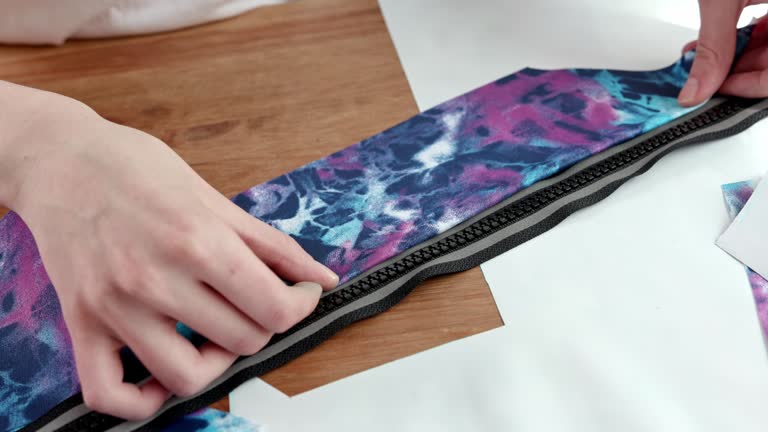 Cropped image of beautiful young designer working with sketches and measure tape in dressmaking salon