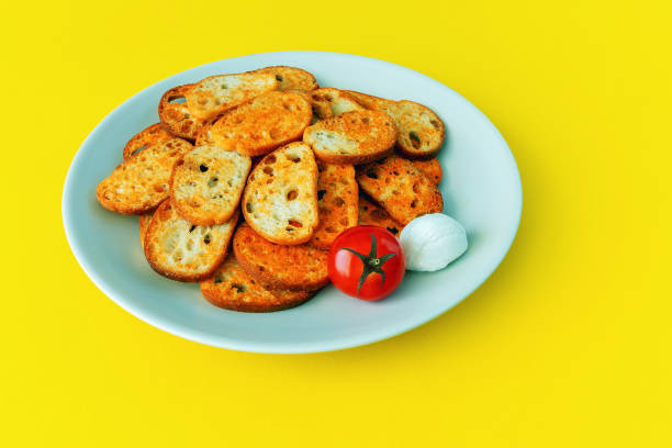 Toasted bread slices with tomato and mozzarella flavor on a plate on a yellow background