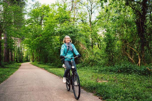 istock Senior woman cycling through forest trail 2157804003