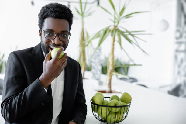 istock Dark-skinned businessman eating an apple and looking contented 2157806357
