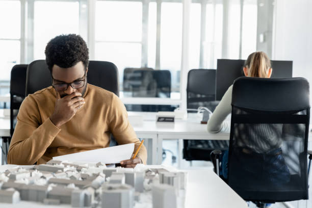 istock Dark-skinned young architect working in the office and looking tired 2157806454
