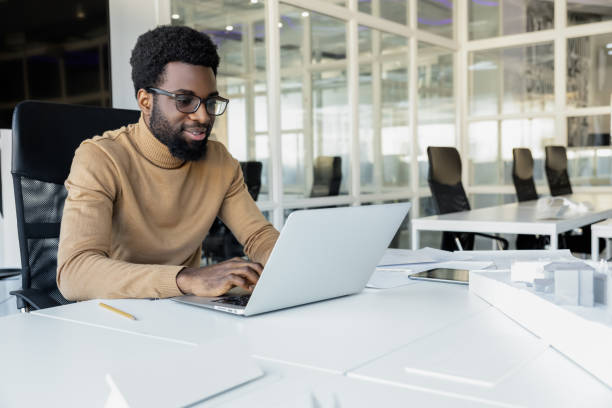 istock Young dark-skinned man working on the laptop in the office 2157806478