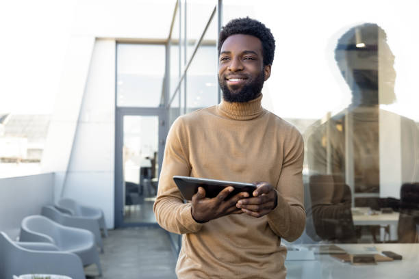 istock Smiling dark-skinned man in casual clothes with tablet in hands 2157806502