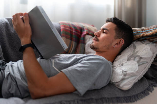 istock young man lying on a a sofa with domestic cats reads a book 2157810236