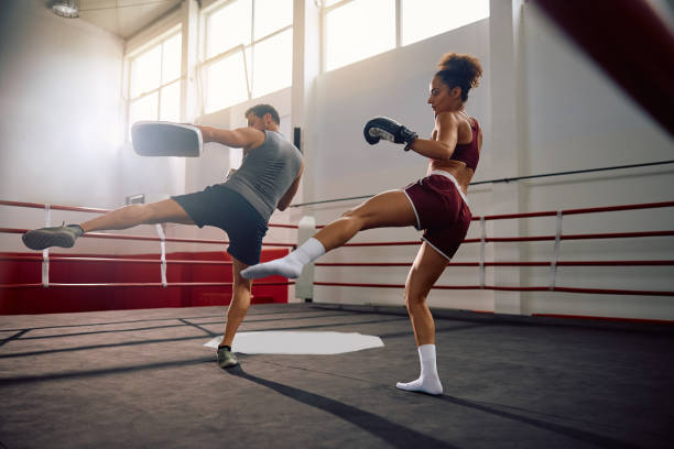istock Female boxer exercising with her instructor in boxing ring. 2157813913