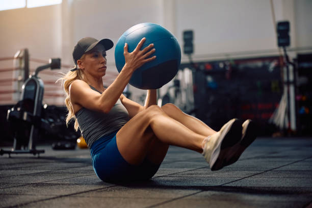 istock Athletic woman using medicine ball while doing sit-ups during sports training in a gym. 2157815220