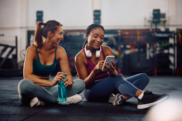 istock Happy athletic women using smart phone during water break in a gym. 2157815287