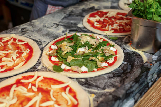 istock making pizza on the table. Pizza with ingredients. Tomatoes, mozzarella cheese, pepper, and parmesan cheese on dark wooden background. Food, family and people concept. 2157819442