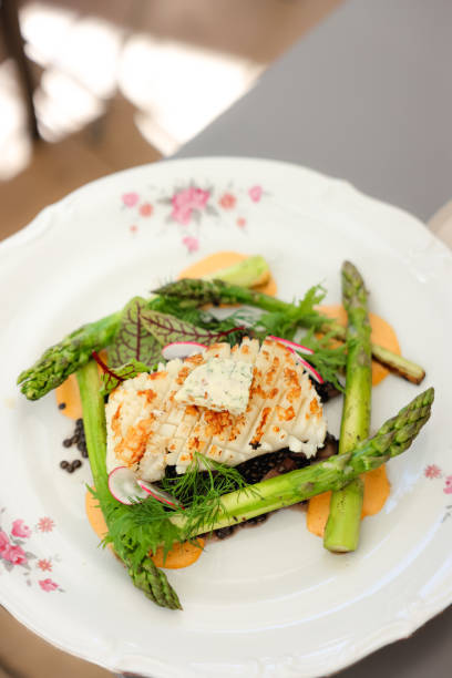 Close-up view of gourmet meal with seafood and vegetables with blue cheese served in French style plate on the table with plant in cafe patio during sunny day
