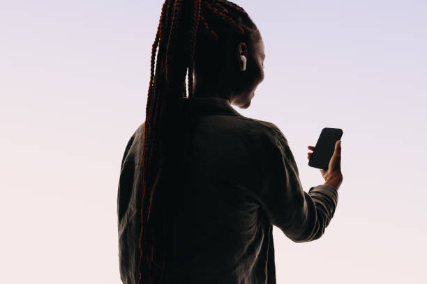 istock Happy young woman smiling while making a video chat on her smartphone, studio silhouette 2157826307