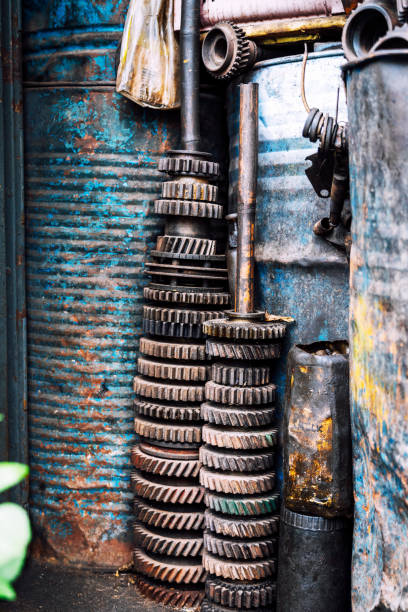 Close-up of a stack of old metal gears in an aged industrial workshop. Depicts machinery, rust, and vintage industry elements.