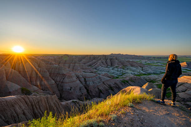 Hiker Enjoying a Vibrant Sunrise Over Panorama Point's Beautiful Geological Rock Formations in Badlands National Park in South Dakota USA