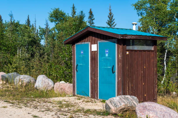 Blue restroom outhouse, rocks, against trees forest background