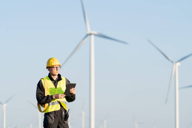 istock Engineer with digital tablet works on a field of wind turbines 2157840892