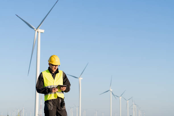 istock Engineer with digital tablet works on a field of wind turbines 2157841009