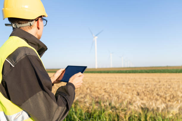 istock Engineer with digital tablet works on a field of wind turbines 2157841142