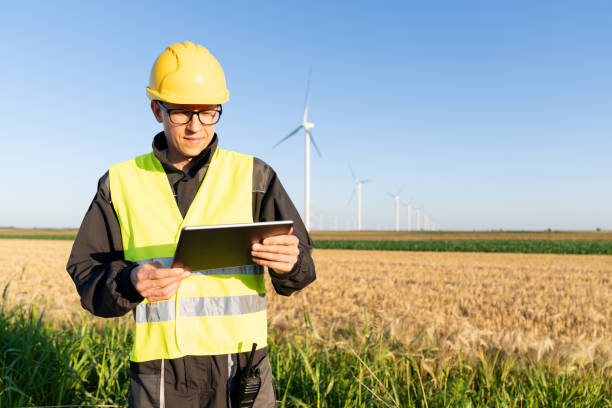 istock Engineer with digital tablet works on a field of wind turbines 2157842300
