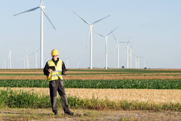 istock Engineer with digital tablet works on a field of wind turbines 2157842382