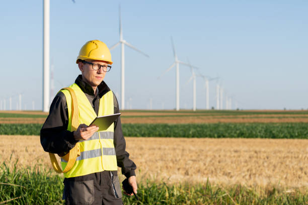 istock Engineer with digital tablet works on a field of wind turbines 2157844401