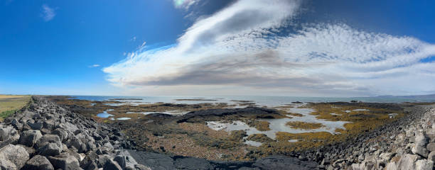 istock Rocky Shoreline and Expansive Sky With Clouds on a Sunny Day 2157846440