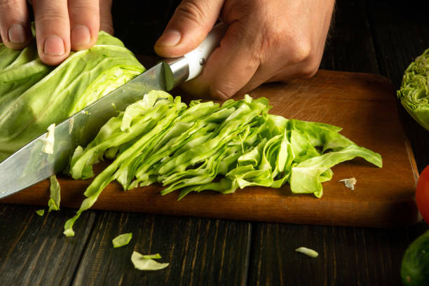 istock Close-up of a chef hands using a knife to cut fresh cabbage before preparing a vegetarian dish on the kitchen table 2157851843