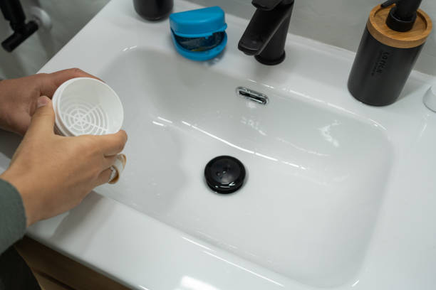 istock Unrecognizable man's hands holding empty denture cleaning glass by bathroom sink, promoting daily dental hygiene. 2157854734
