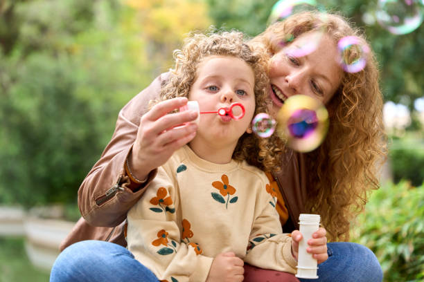 istock A woman and a child are blowing bubbles in a park 2157855517