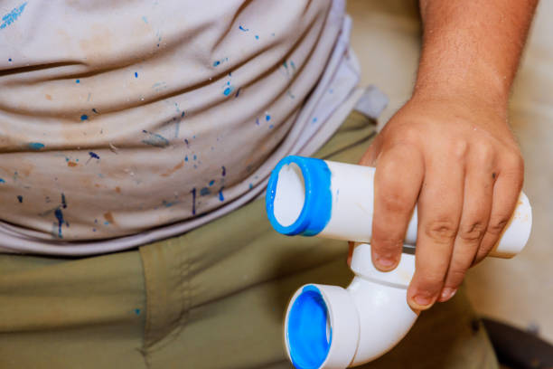 Male Worker Inspecting Water Pipes For Leaks In Basement