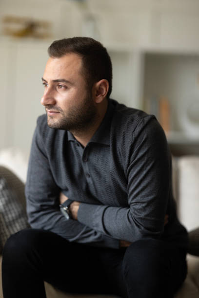 istock Thoughtful serious man sitting on sofa at home, lost in thoughts 2157860106