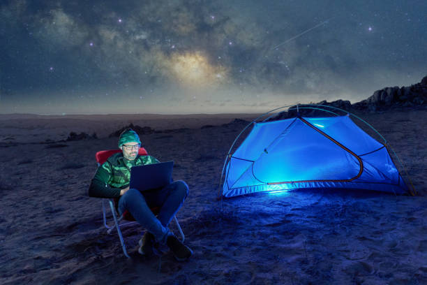 istock digital nomad man sitting alone with a laptop camping in the desert at night 2157860802