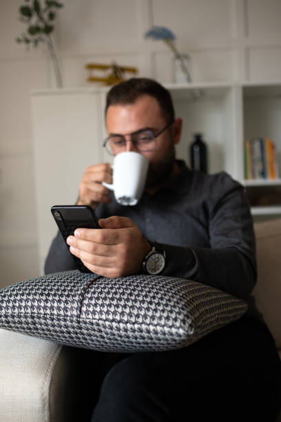 istock Man with eyeglasses stand at home use mobile phone sms texting 2157860882