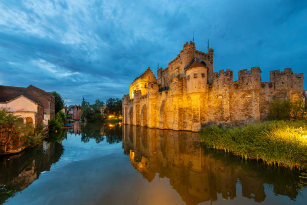 Ghent, Belgium - March 29, 2025: canal boat on the Lieve river passing the historic houses along the Augustijnenkaai in the centre of the Belgian city of Ghent