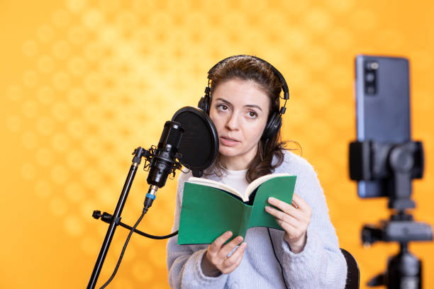 istock Media star filming vlog at work, reading book to record audiobook 2157867256